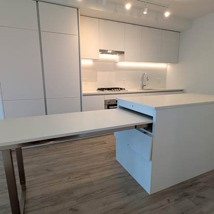 a modern kitchen with a white countertop and a stainless steel refrigerator.