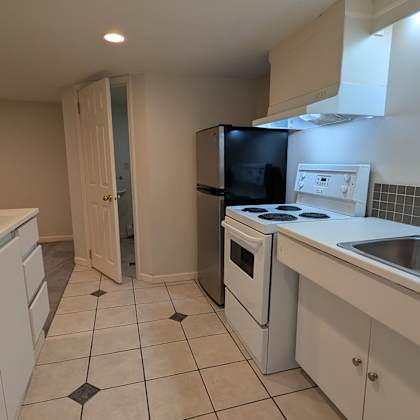 a kitchen with white cabinets and a black fridge.