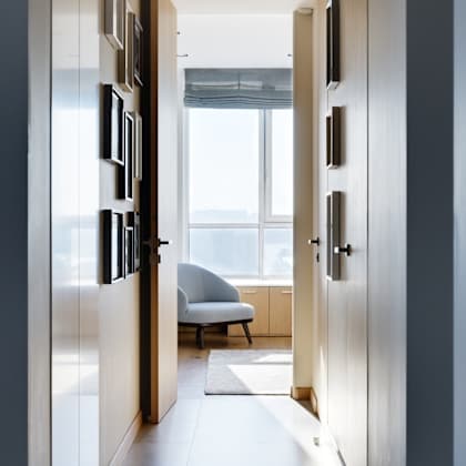 a long hallway with doors on both sides and a chair in the distance.