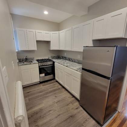 a kitchen with white cabinets and a stainless steel refrigerator.