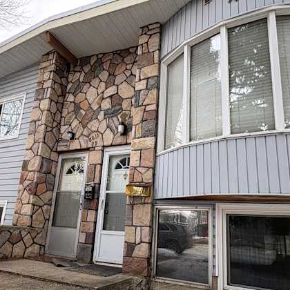 a house with a grey siding and a stone pillar.