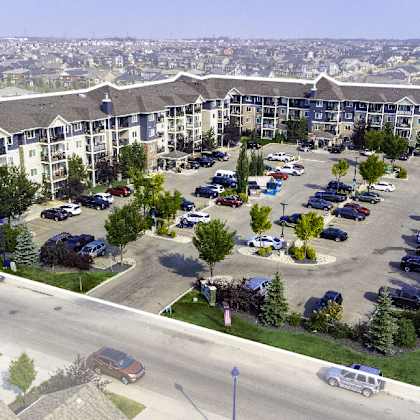 a large apartment complex with a parking lot in front.