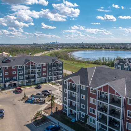 a large apartment complex with a parking lot in front.