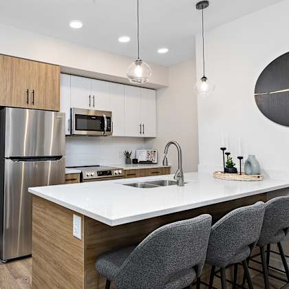 a modern kitchen with a large island and grey chairs.
