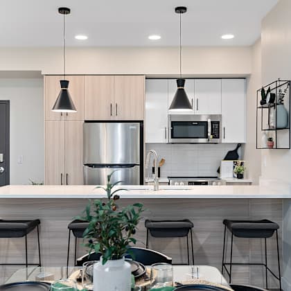 a modern kitchen with a white countertop and black bar stools.