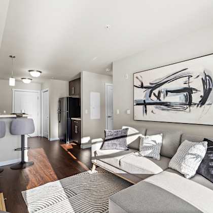 a modern living room with a grey couch and a large abstract painting on the wall.