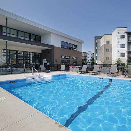 a large swimming pool in front of a building with apartment complexes in the background.