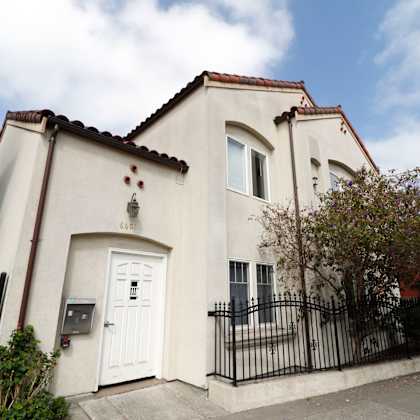 a white house with a black gate and a brown roof.