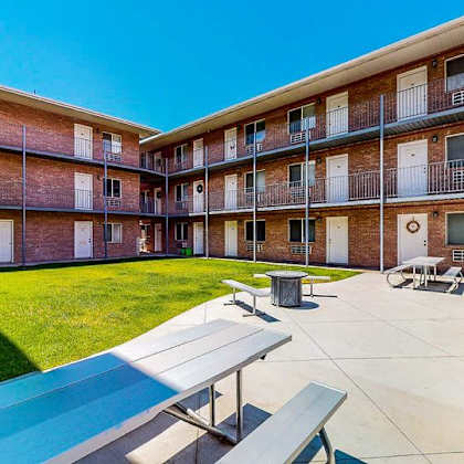 a sunny day at the apartment complex with blue skies and green grass.