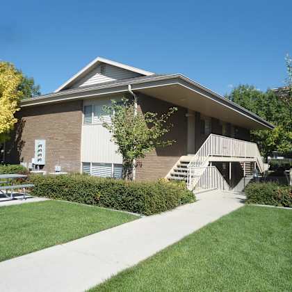 a building with a brown roof and a white awning is surrounded by greenery.