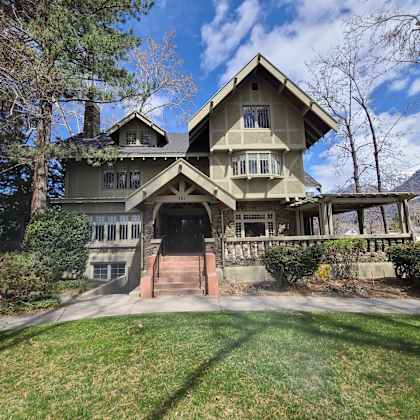 a large house with a triangular roof and a stone wall.