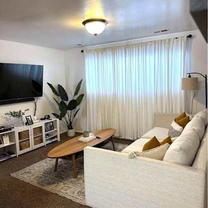 a living room with a white couch, a wooden coffee table, and a flat screen tv.