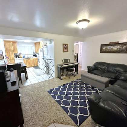 a living room with a black leather couch and a rug.