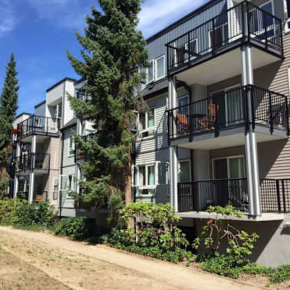 a row of apartment buildings on a sunny day with a dirt path in front of them
