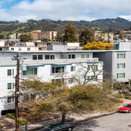a parking lot with cars and apartment buildings in the background.