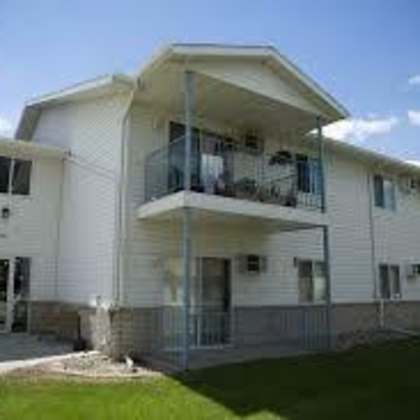 a white two-story apartment building with balconies on the second floor.