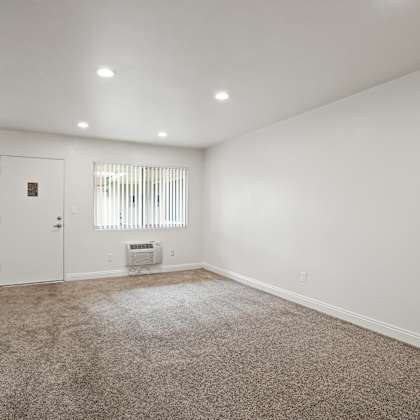 a room with a carpeted floor and a window with blinds.