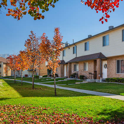 a row of houses with trees in autumn colors in front.