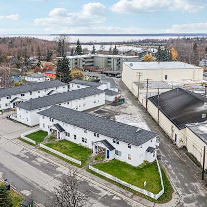 a large white building with a black roof is surrounded by other buildings and trees.