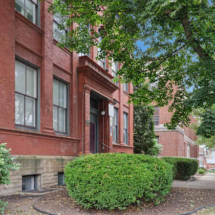 a red brick building with a green bush in front.