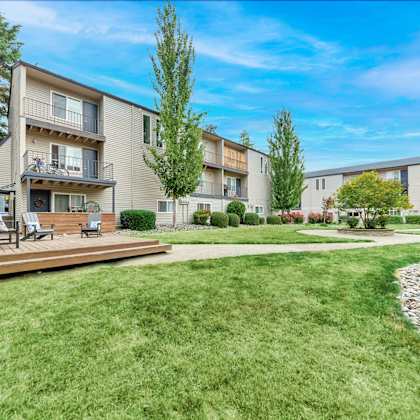 a sunny day at a well-kept apartment complex with a green lawn and trees. at river lofts apartments, tualatin, oregon