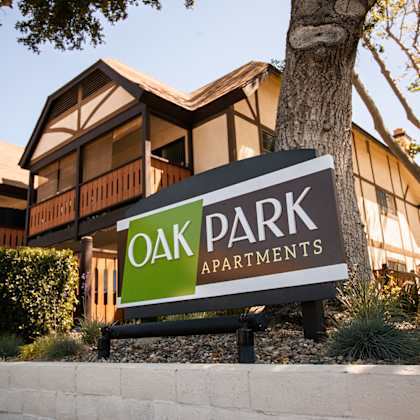 a sign for oak park apartments in front of a tree at oak park apartments, california