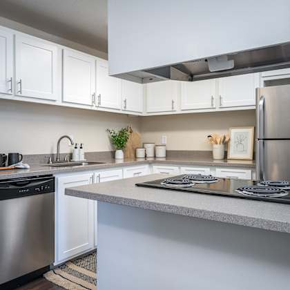 a kitchen with white cabinets and stainless steel appliances and a counter top at sundial apartments, oregon