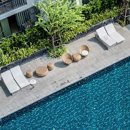 a hotel pool with chairs and umbrellas next to a swimming pool