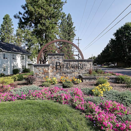 a sign that reads biltmore apartments in front of a garden with flowers