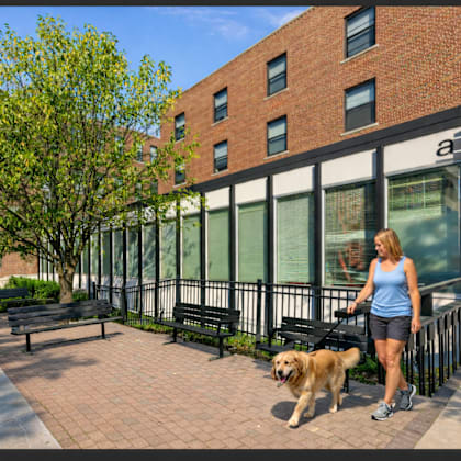 a woman walking her dog in front of a brick building.