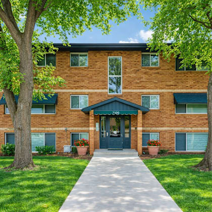 a brick building with a green awning and a tree in front.