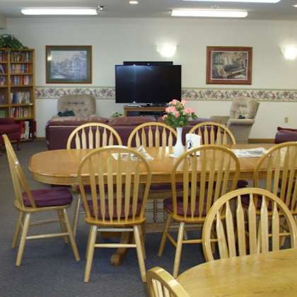 a room with a wooden table surrounded by chairs and a television on the wall.