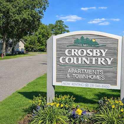 a sign for crosby country apartments and townhomes with a phone number for renting.