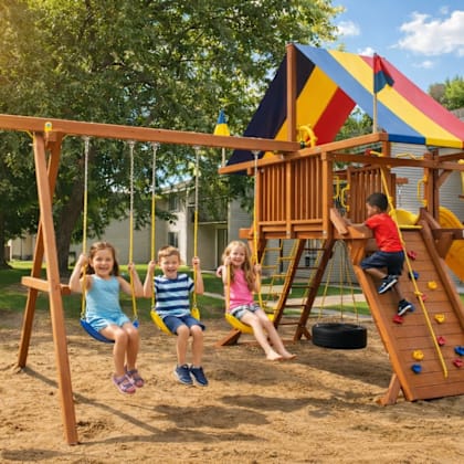 three children playing on a swing set in a sandy area.