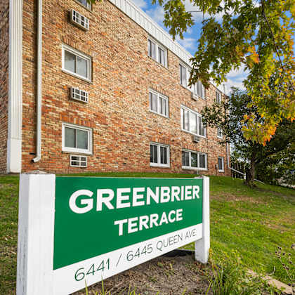 a sign for greenbrier terrace stands in front of a brick building.