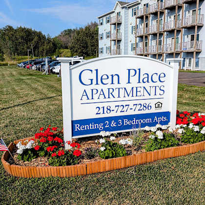 a sign for glen place apartments in front of a garden of flowers