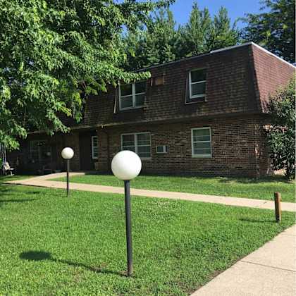 a white ball on a black pole in front of a brick house.