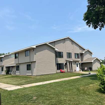 a large, modern house with a grey exterior and a well-maintained lawn.