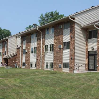 apartment building with brick exterior and a green lawn in front.