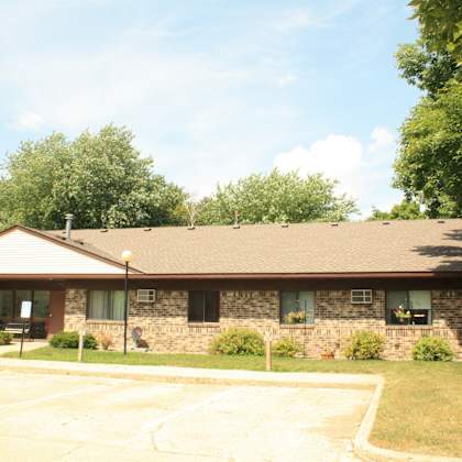 a building with a brown roof and stone walls with a parking lot in front.