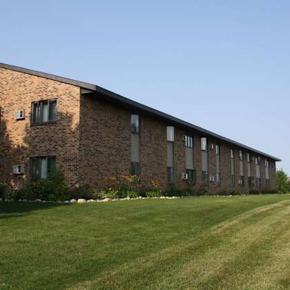 a long brick building with a green lawn in front.