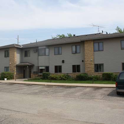 a grey building with a parking lot in front.