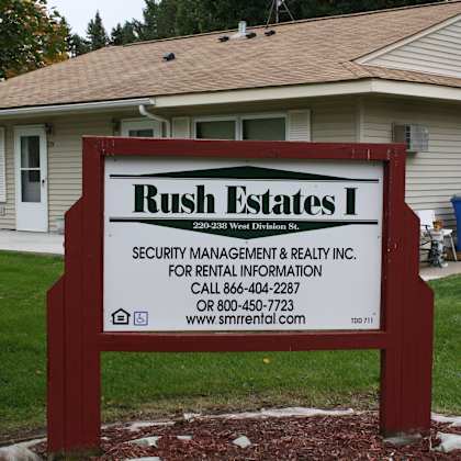 a sign for rush estates security management & realty inc. in front of a house.