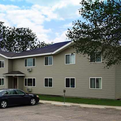 a black car is parked in front of a tan building.