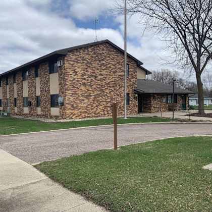 a building with a stone facade and a grassy area in front.