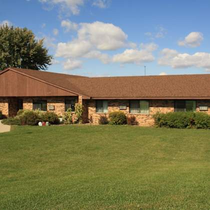 a building with a brown roof and a green lawn in front.