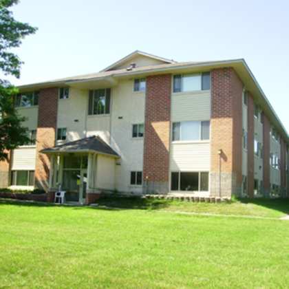 a large apartment building with a green lawn in front.