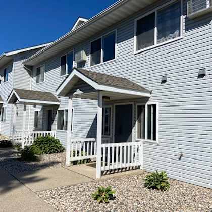a row of houses with white fences and grey siding.