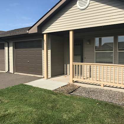 a house with a grey garage door and a brown wooden fence.