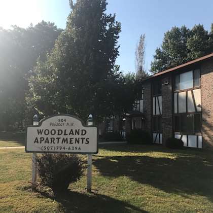 a sign for woodland apartments stands in front of a building.